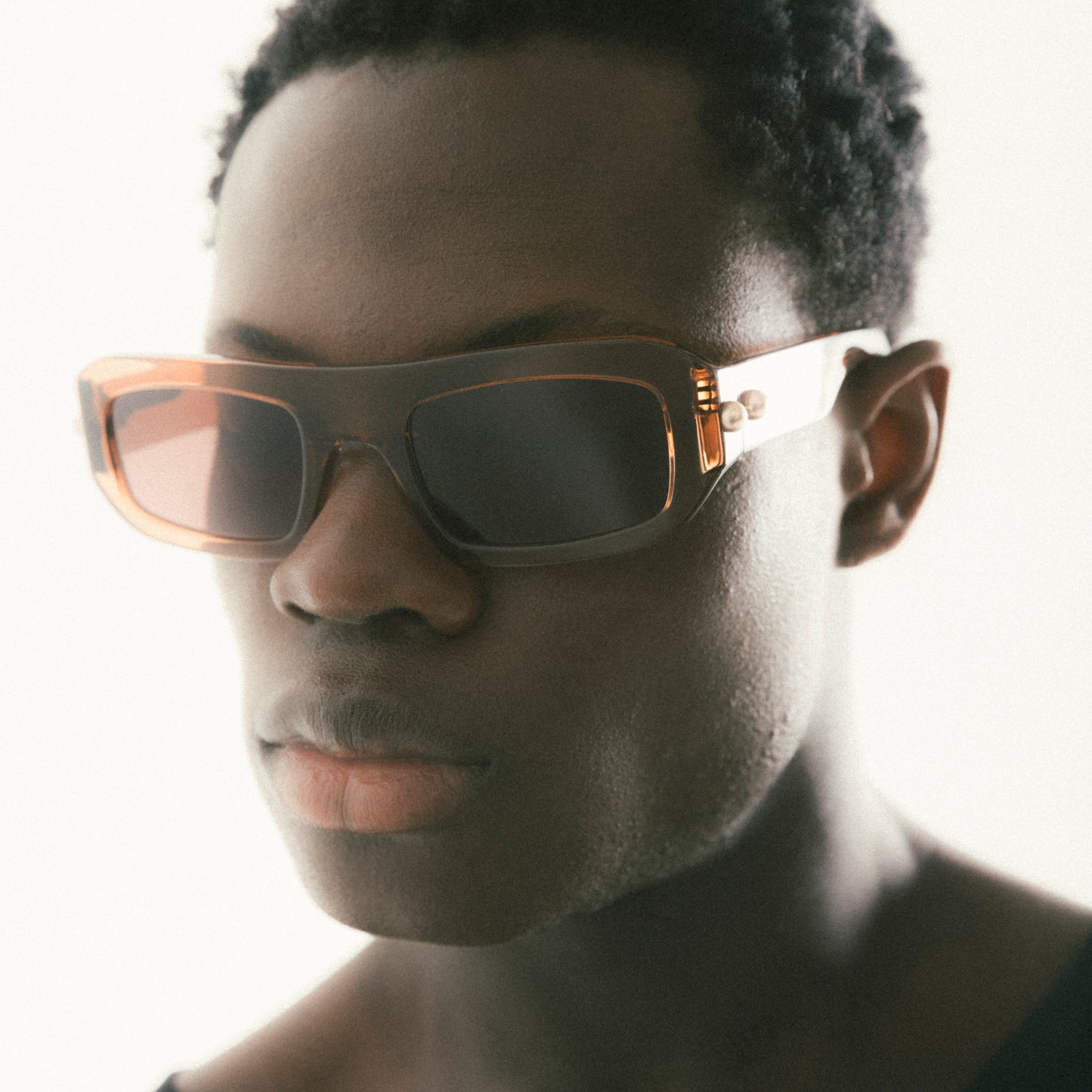 Transparent brown rectangular acetate sunglasses worn by male model side view studio image