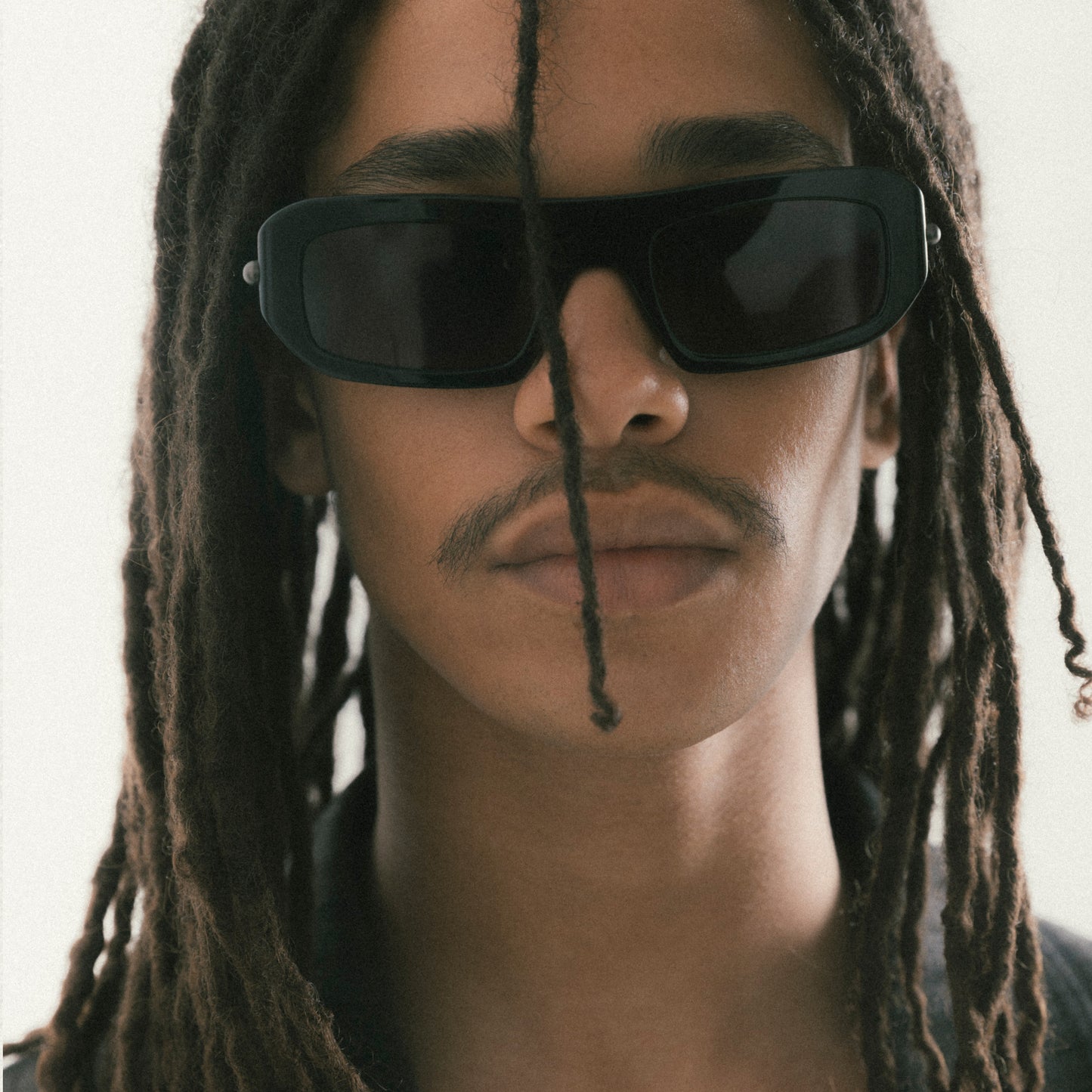 Black rectangular acetate sunglasses worn by male model – front-facing portrait on neutral background