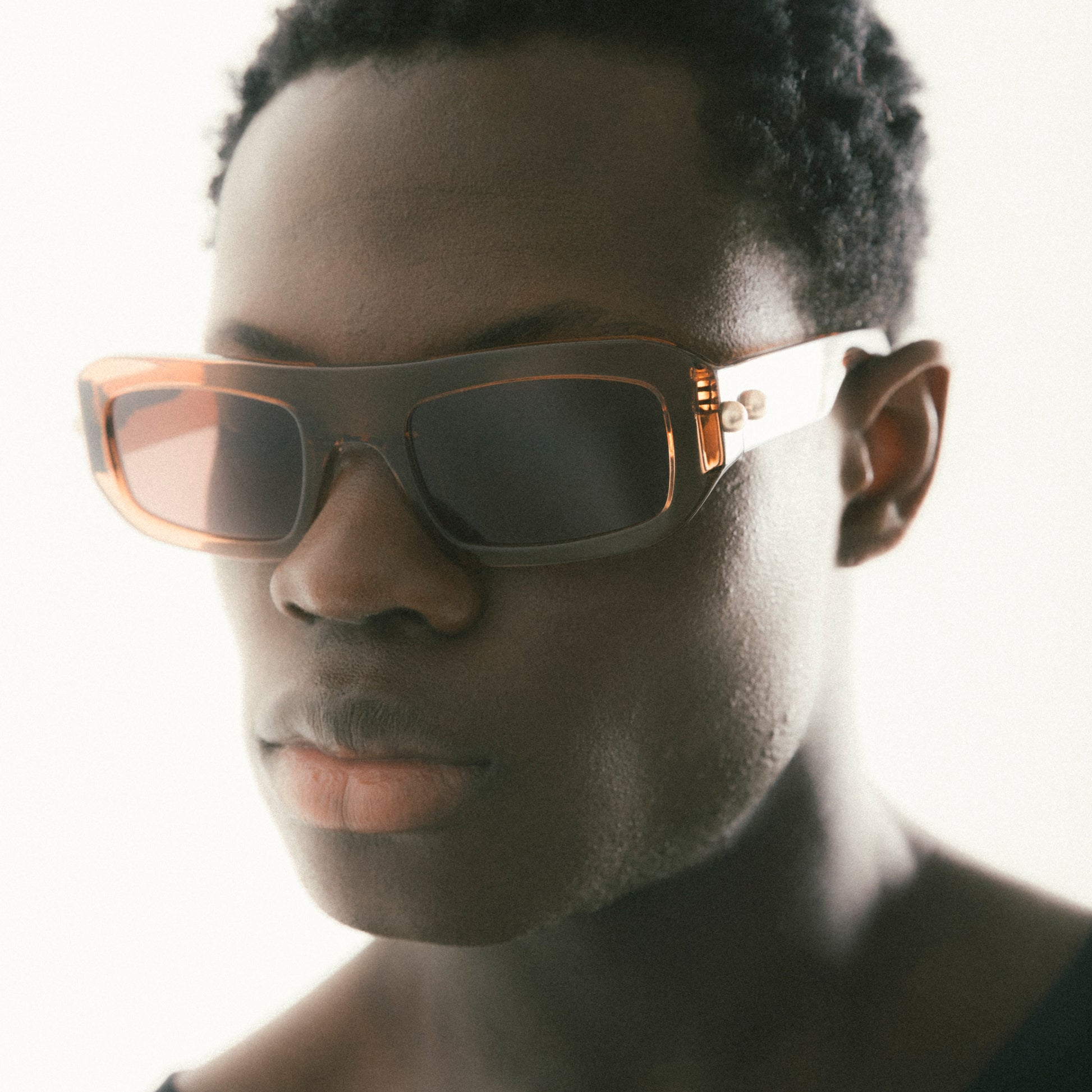 Transparent brown rectangular acetate sunglasses worn by male model side view studio image